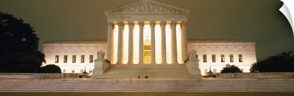 Large, panoramic, low angle photograph of the Supreme Court Building in Washington DC, brightly lit at night.