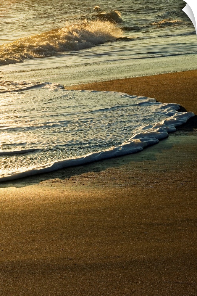 A vertical photograph of waves washing up on the shore in the morning.
