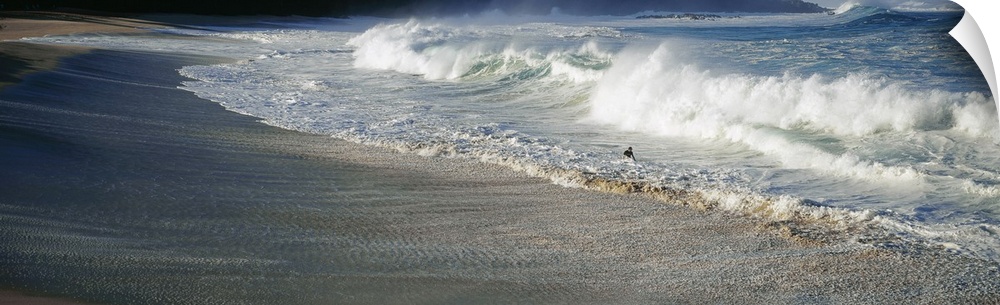 A figure with a surfboard is dwarfed by the gigantic waves on the Hawaiian coastline in the early morning.