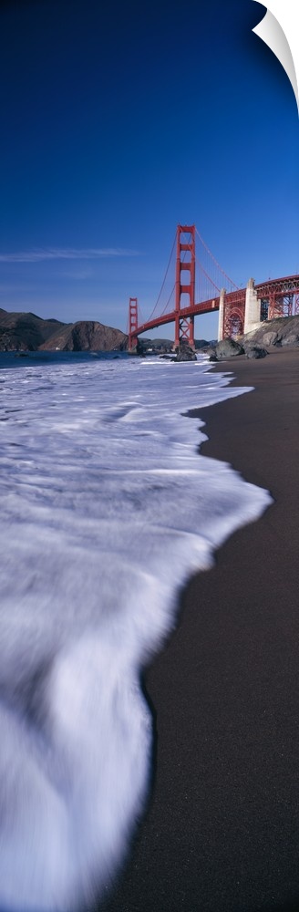 Large, vertical photograph looking down the shoreline of the San Francisco Bay, the Golden Gate Bridge in the background b...