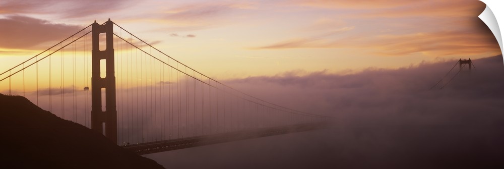 Panoramic photo on canvas of the silhouette of the Golden Gate Bridge coming out of the fog at sunset.