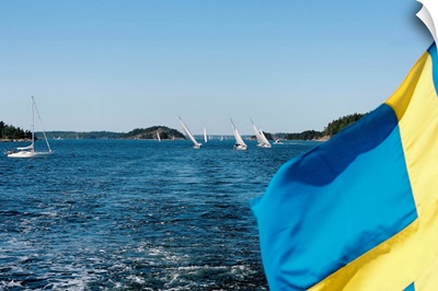 Swedish flag with sailboats in the background, Stockholm Archipelago, Sweden