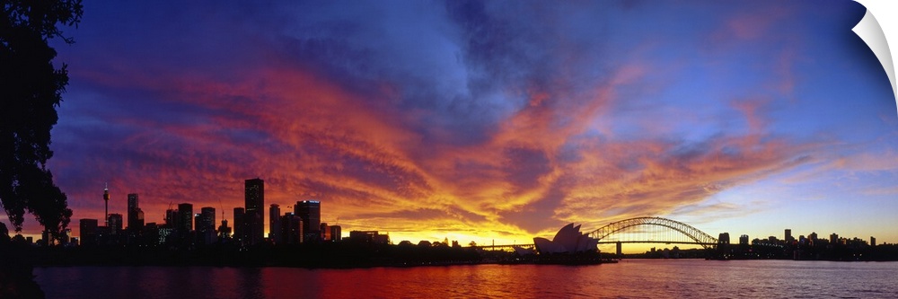 The Sydney skyline is photographed in panoramic view as the sky is lit up with vibrant colors from the sunset.