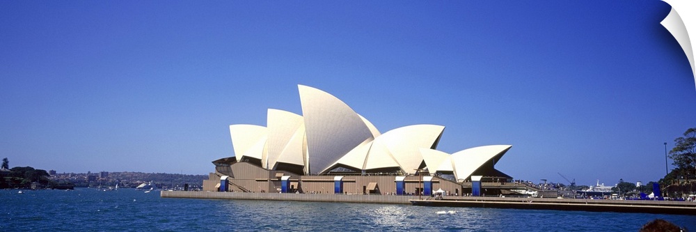 Panorama of the Sydney Opera House in front of a blue Australian sky.