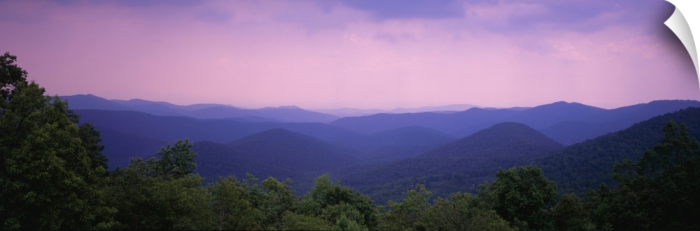 Wide angle photograph taken of the smoky mountains with some trees lining the bottom of the picture.