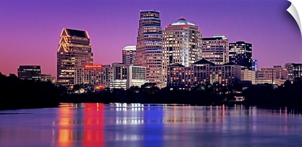 Big cityscape of the downtown of a southern city illuminated at night reflected onto the waterfront.