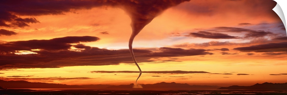 A large panoramic shot of a tornado touching down with a sunset sky stretching across the entire piece.