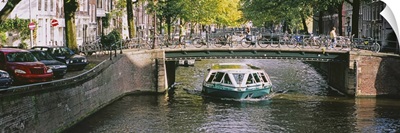 Tourboat under a bridge in a channel, Amsterdam, Netherlands