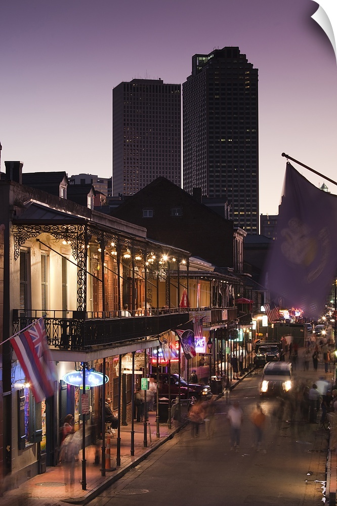 People stroll down Bourbon Street in the French Quarter in New Orleans, Louisianna (LA) at dusk with skyscrapers looming i...