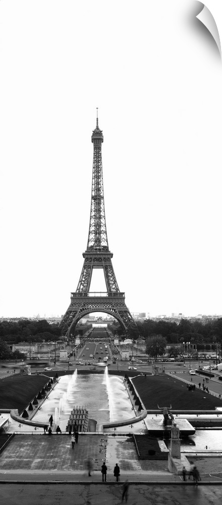 Black and white photograph of the Eiffel Tower as seen from the edge of the plaza. The tower contrasts sharply with the ov...