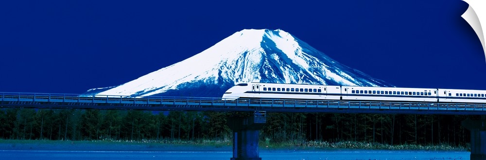 Panoramic photo on canvas of a train going across a bridge above water with a snowy mountain the background.