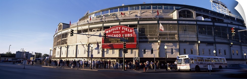 Wrigley Field is photographed in wide angle view with crowds standing in the front of the stadium waiting to get in as the...
