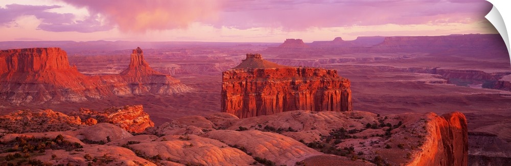 Wide angle, aerial photograph of the rocky terrain at Canyonlands National Park in Utah, beneath a pastel sky.