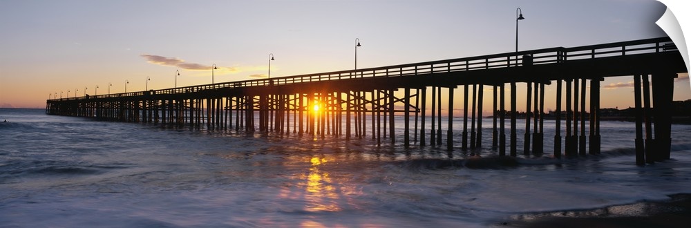 Panoramic photo on canvas of the silhouette of a pier going out into the ocean against a sunset.