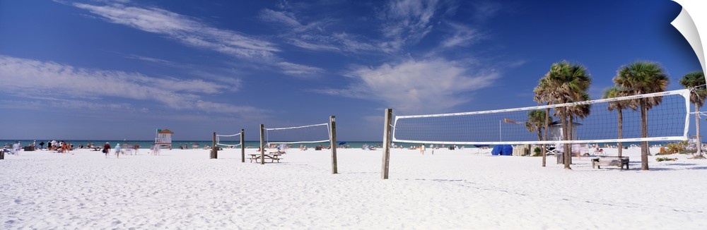 Row of empty volleyball courts on the white sand beach on a clear day.