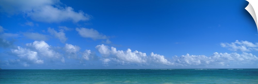 Panoramic photograph of ocean under a cloudy sky.