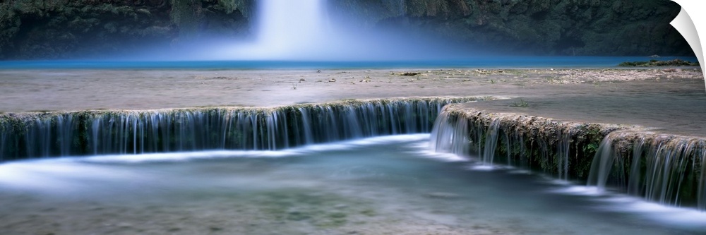 This is a panoramic, time lapsed photograph of water flowing over shallow waterfalls in a desert oasis.
