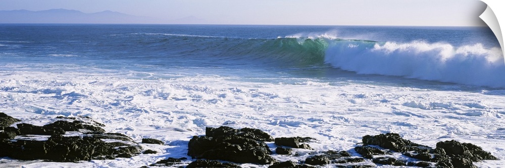 Long image on canvas of big waves crashing onto a rocky shore.