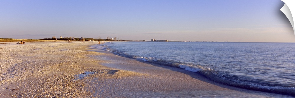 Panoramic photograph looking down the shoreline of Fort Myers Beach beneath a blue sky, in the Gulf of Mexico, Florida.