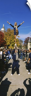 Woman standing one leg on a man hand and performing a stunt, University Of Notre Dame, South Bend, Indiana