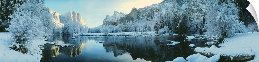 Giant, panoramic photograph of calm waters surrounded by snow covered trees and mountains in Yosemite National Park, Calif...