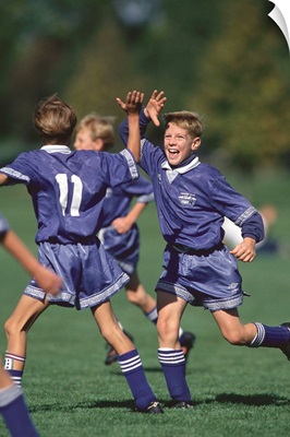 Boys soccer players celebrate a goal.