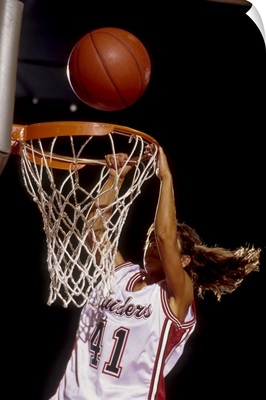 Female basketball player slam dunking