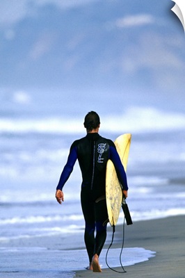 Male surfer walking on the beach in San Diego, CA