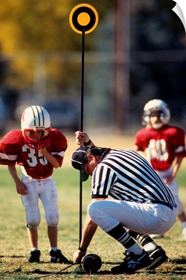 Referee measuring for a first down during a pee wee football game