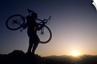 Silhouette of mountain biker at the summit during sunrise