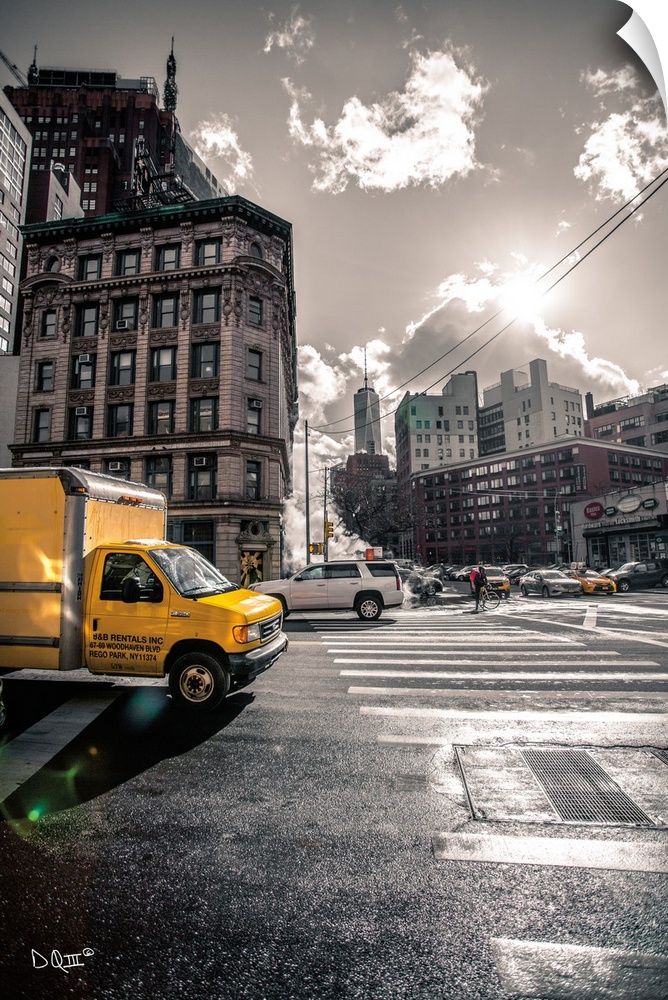 Photograph of a yellow truck popping against a subdued city street scene.