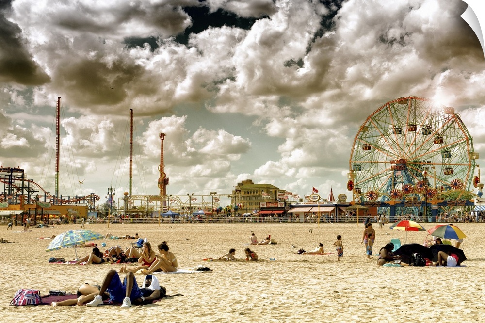 Photo of dramatic clouds over the sandy beach of Coney Island with carnival rides in the background.