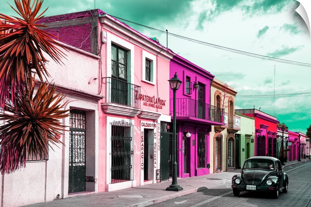 Colorful photograph of pink facades and a black Volkswagen Beetle driving down the street. From the Viva Mexico Collection.