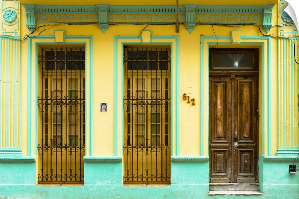 Photograph of a turquoise and yellow building facade with two windows and a wooden door in Havana, Cuba