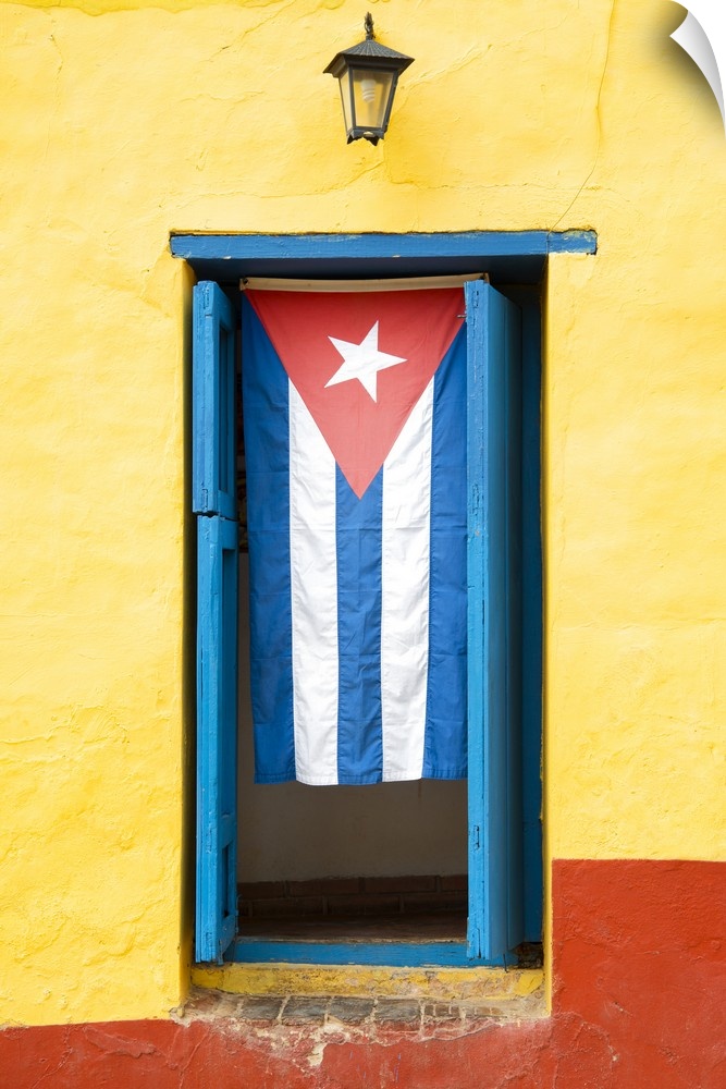Photograph of the Cuban flag hanging in a window on a yellow and red wall in Havana.