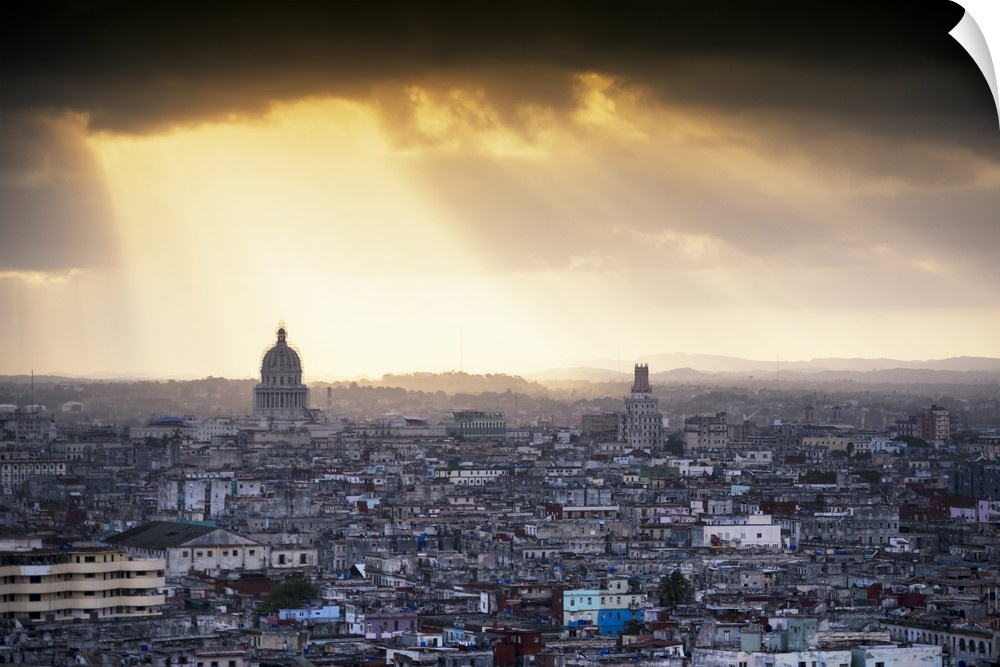 Photograph of the sunrise over Havana, Cuba with large sun beams peering though the clouds and onto the city.
