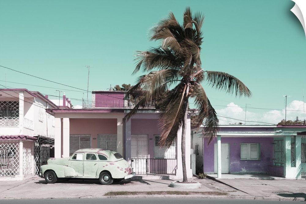 Muted photograph of an old car parked in font of a house in Cuba.