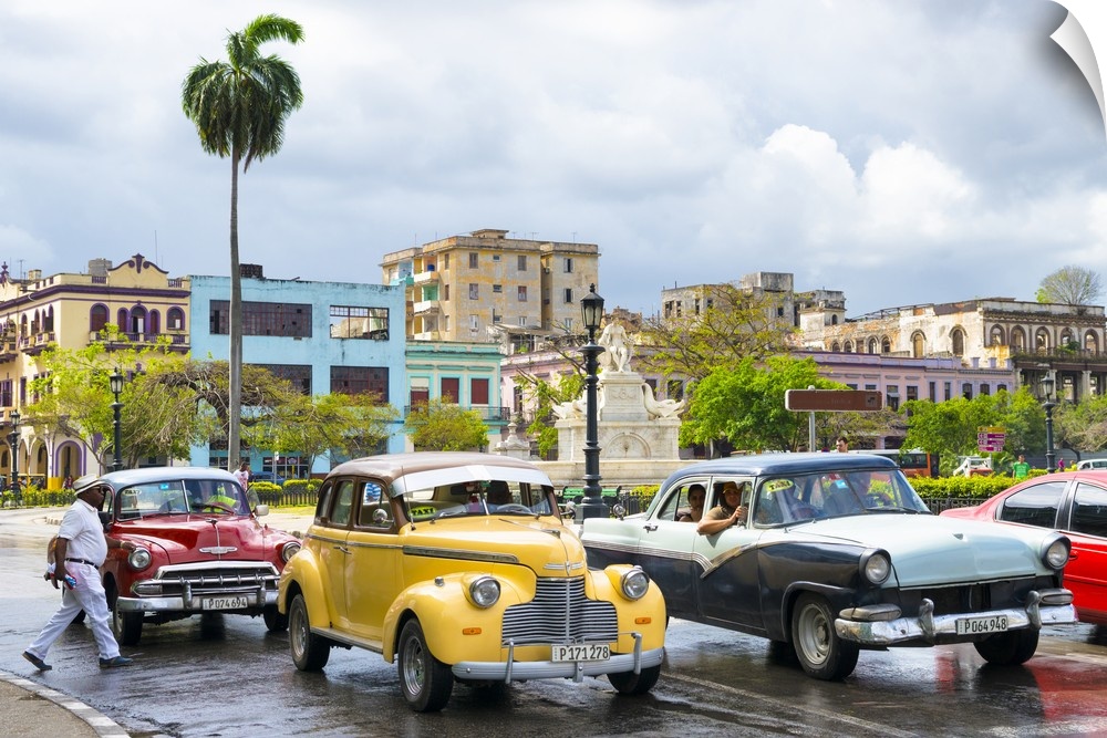 Photograph of a cloudy sky above a wet Havana street scene with vintage cars and taxis.
