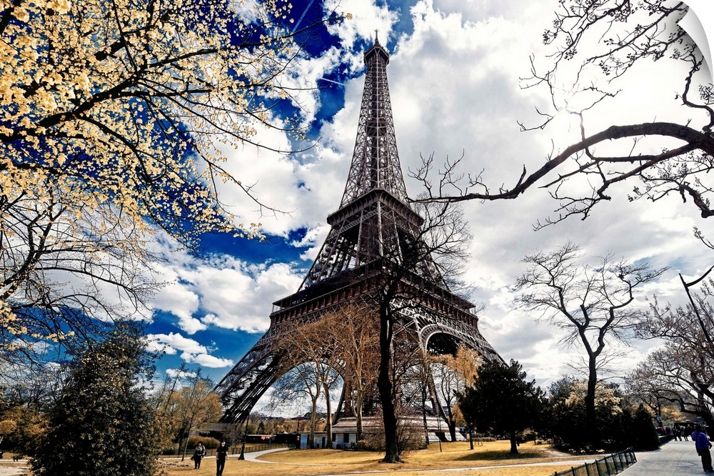 View of the iconic Eiffel Tower from the ground under stunning clouds.