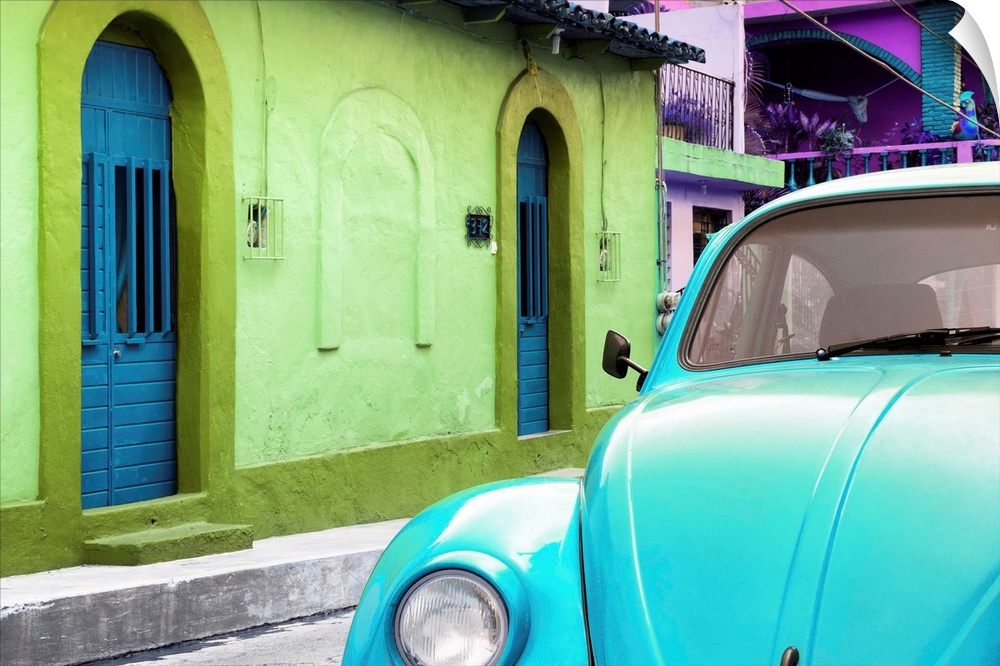 Close-up photograph of a light blue Volkswagen Beetle parked next to colorful houses. From the Viva Mexico Collection.