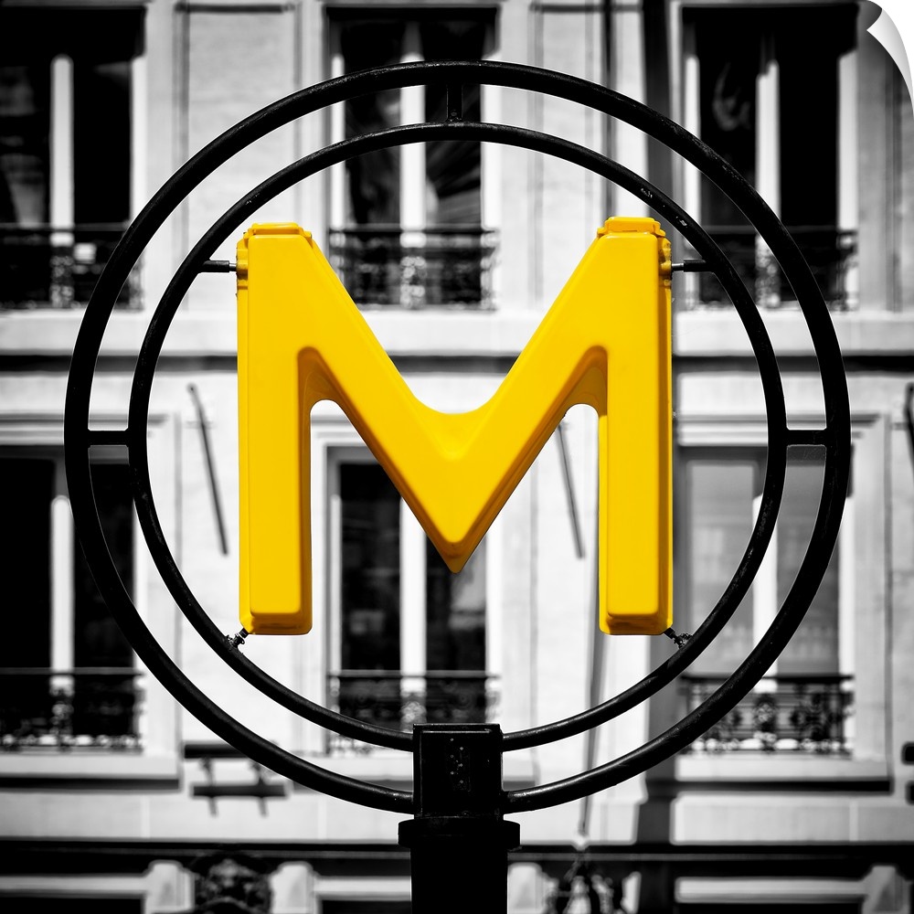 An artistic photograph of a bright yellow M for metro sign against a completely black and white environment.