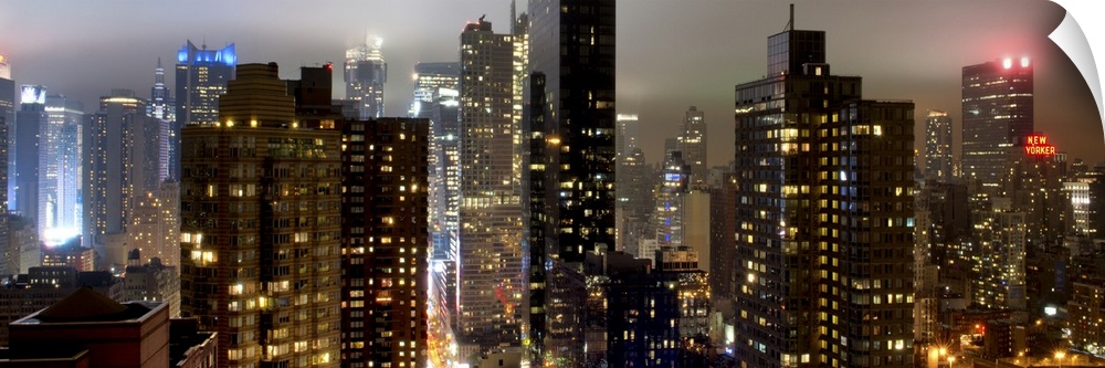 Panoramic photo of the New York city skyline with skyscrapers lit up at night.