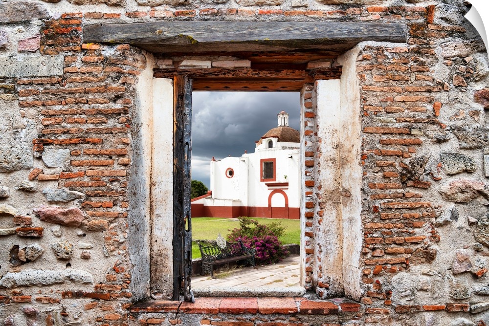 View of a red and white church in Mexico framed through a stony, brick window. From the Viva Mexico Window View.