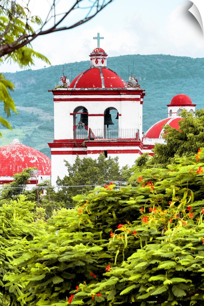 Photograph of a red and white Church surrounded by lush trees and mountains. From the Viva Mexico Collection.