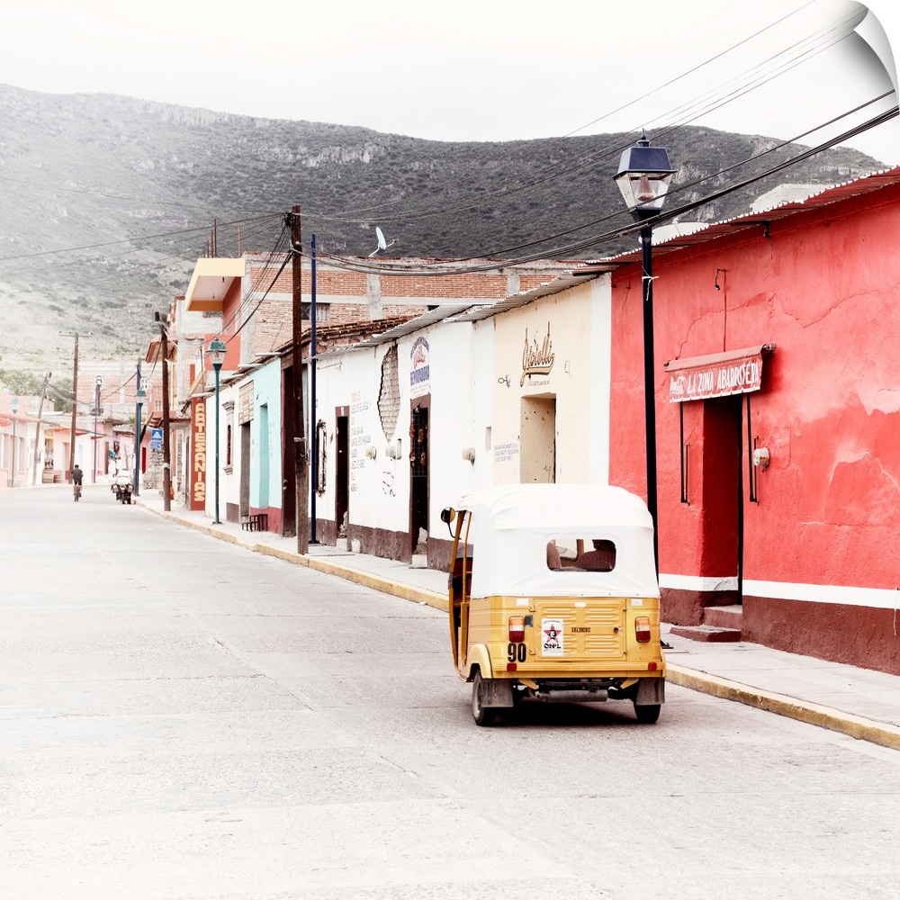 Square ashed out photograph of a Mexican street scene with a yellow Tuk Tuk on the road. From the Viva Mexico Collection.