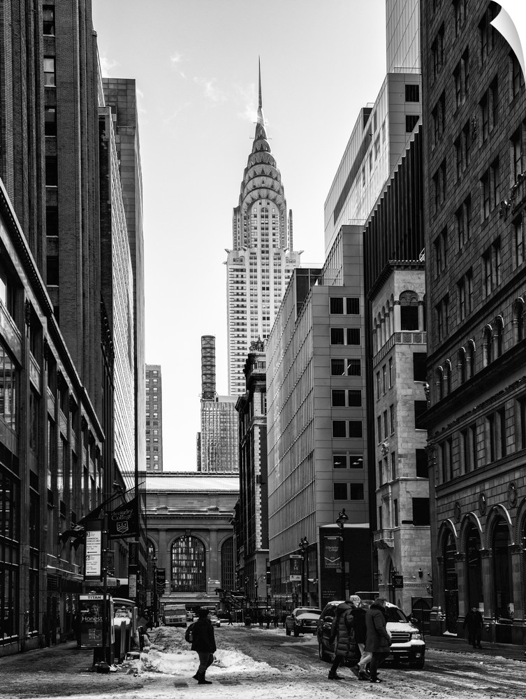 A black and white photograph of the Chrysler building standing tall in NYC, seen from street level.