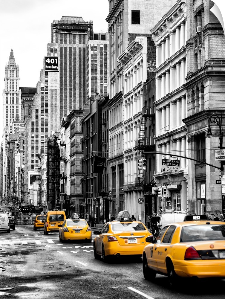 A black and white photograph of New York city with bright yellow colored taxis on the road.