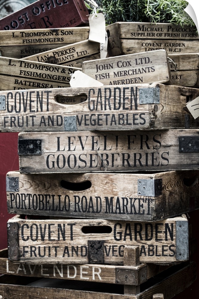 A stack of weathered wooden crates with names of markets lettered on the sides.