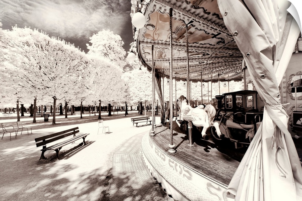It's a winter landscape with a Parisian carousel in the Tuileries Garden in Paris. The trees have white leaves frosted by ...