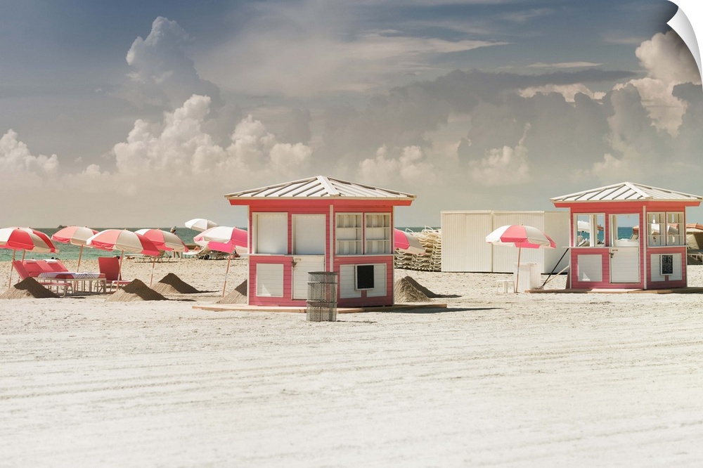 Beach huts with matching umbrellas on the sandy beach on a cloudy day.